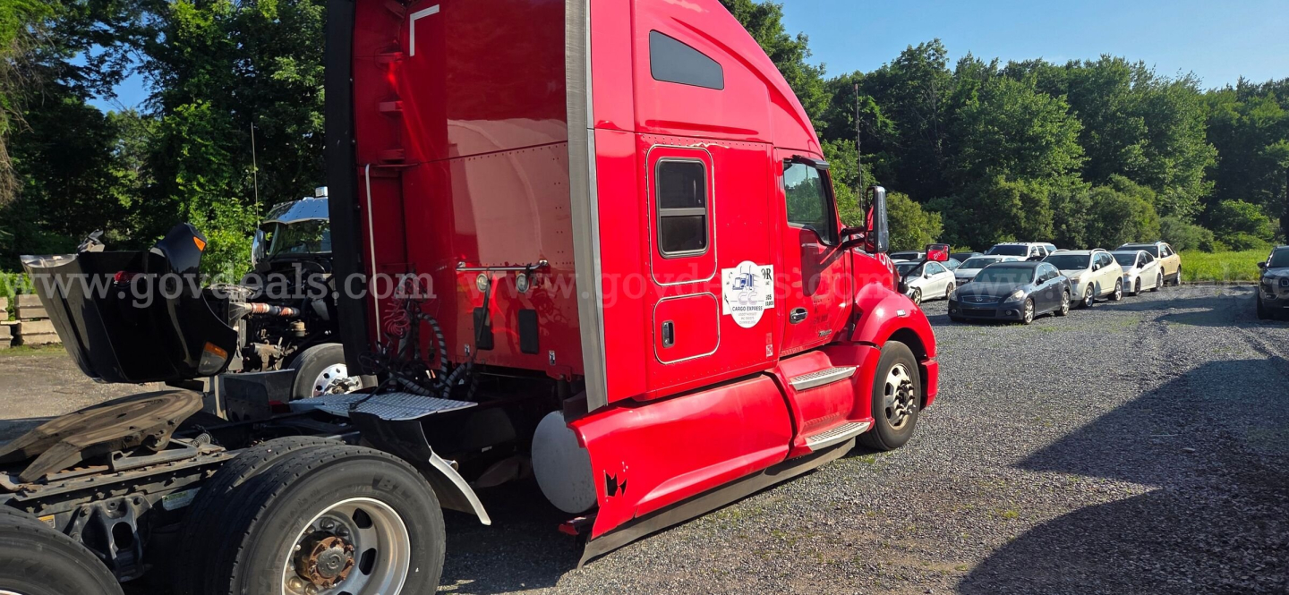 Tractor side view of a red 2020 Kenworth T680 sleeper cab truck showing rear section and driver door with VIN/stock plate nearby.