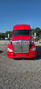 Front view of a red Kenworth truck showing grille, headlights, and chrome bumper. No visible text legible on components.