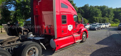 Tractor side view of a red 2020 Kenworth T680 sleeper cab truck showing rear section and driver door with VIN/stock plate nearby.