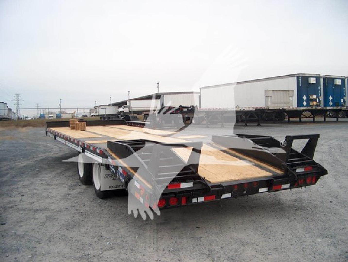 Flatbed trailer with wooden deck and metal framework, rear view showing taillights and support ramps, Thunderbird logo overlay.