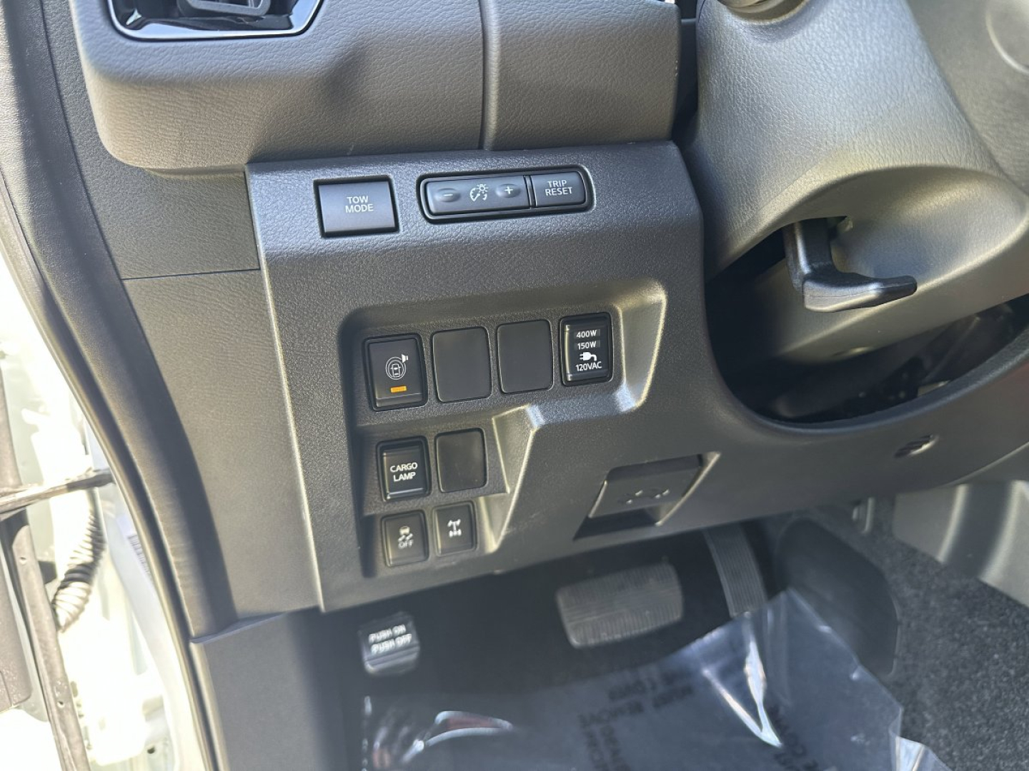 Dashboard controls on the left side of a Nissan Frontier interior showing multiple switches and a steering column in view.