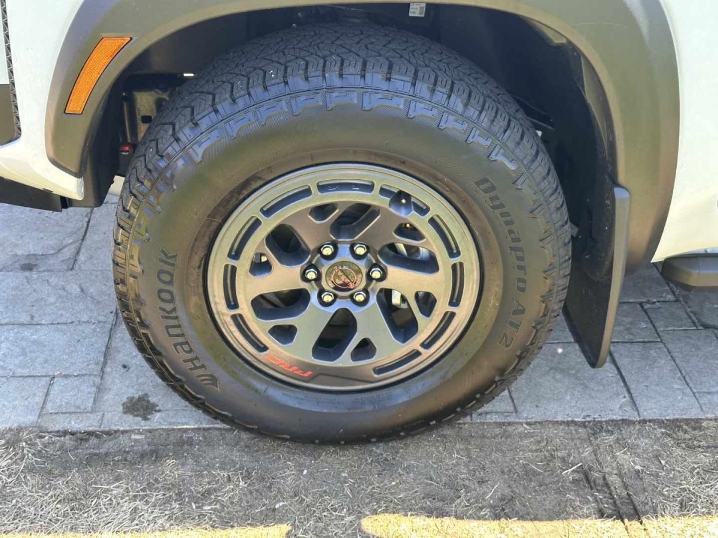 Front wheel and tire close-up on a Nissan Frontier pickup showing Yokohama tire and alloy wheel with center cap. Sidewall text visible.