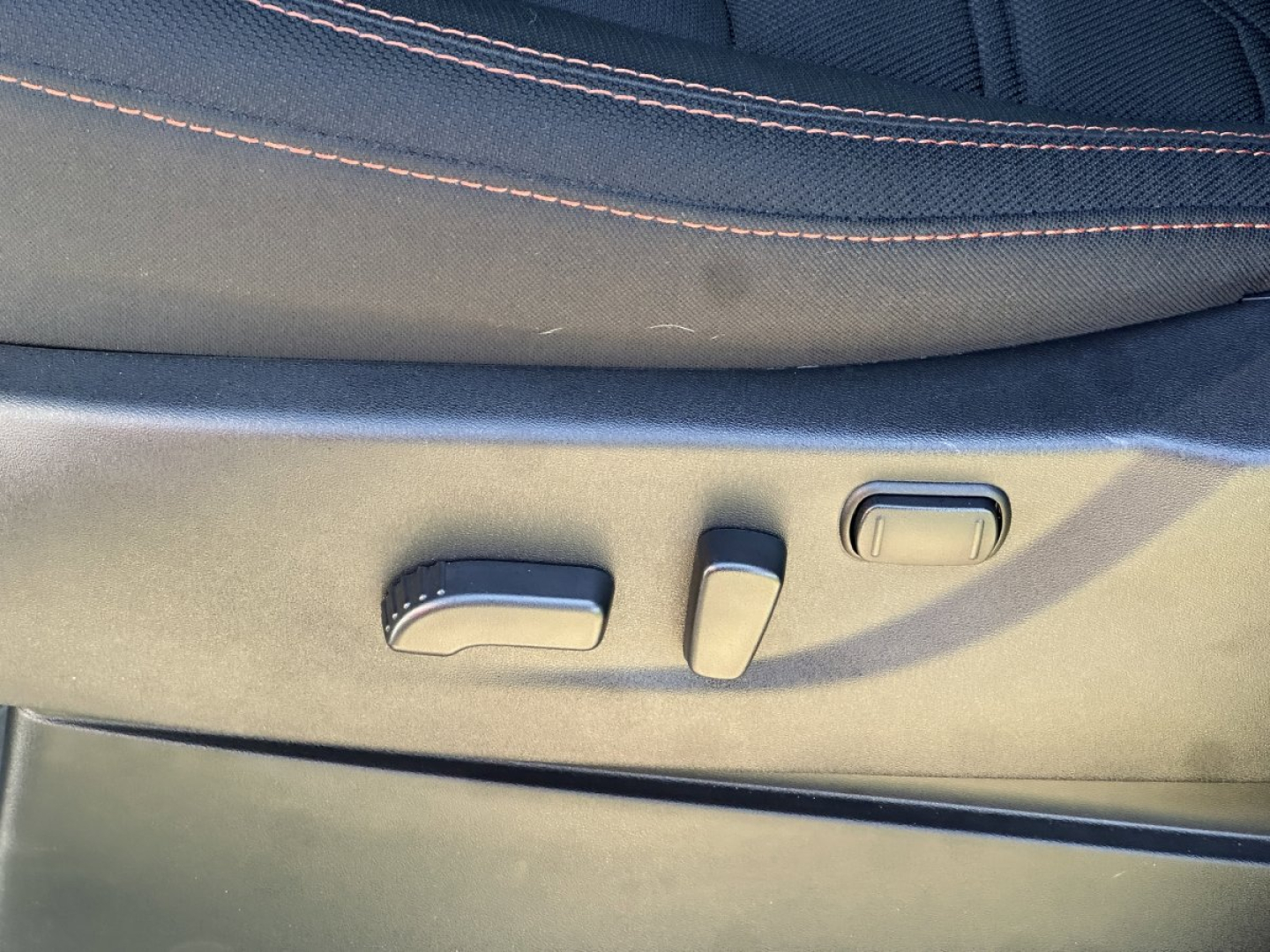 Vehicle seat adjustment controls on a Nissan Frontier interior, showing power recline and lumbar adjustment buttons.