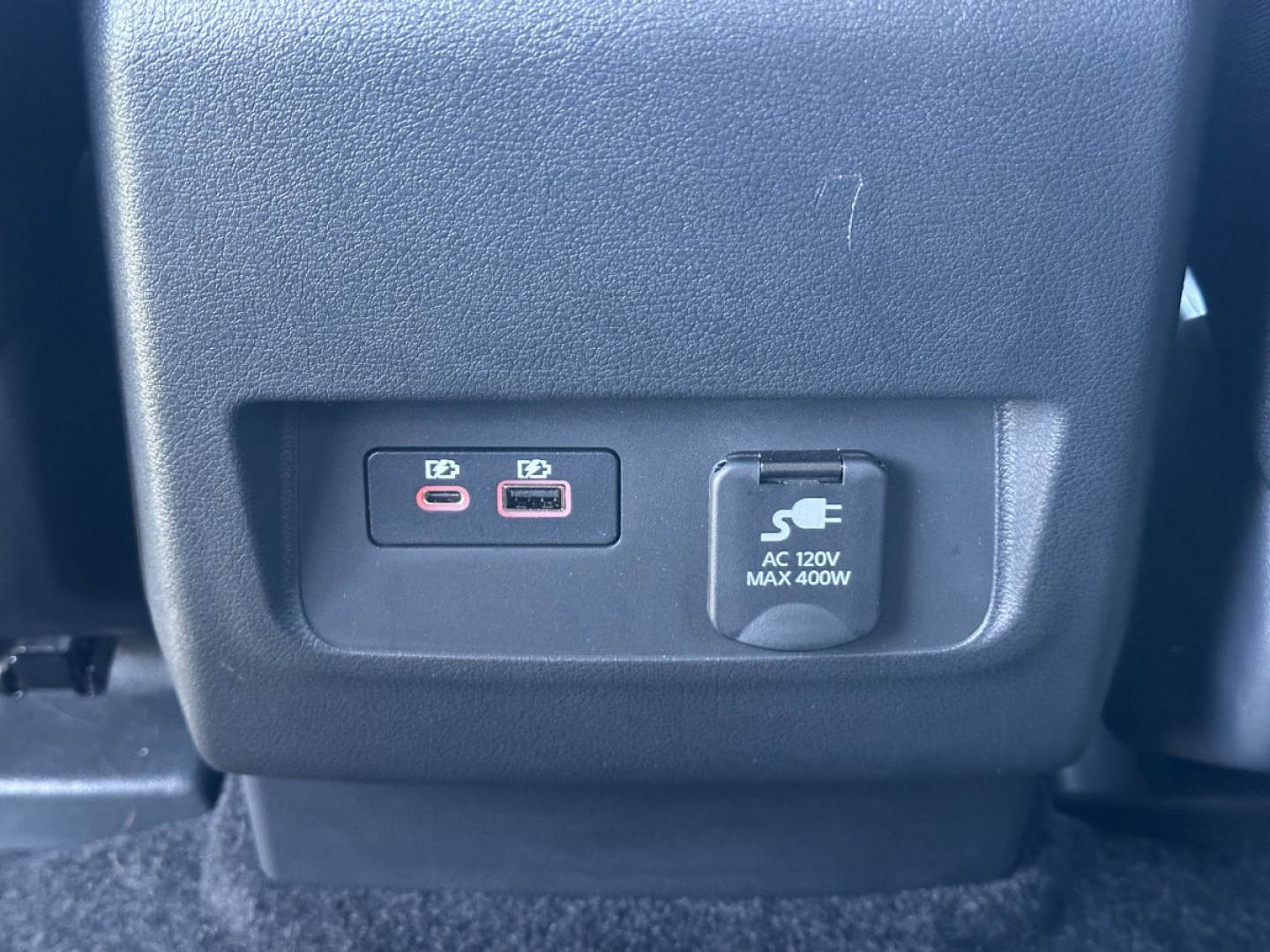Front-seat center console with two USB-C ports and a 12V power outlet in a Nissan Frontier cabin.