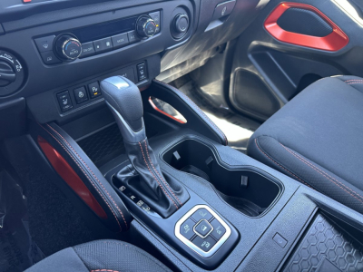 Interior of a 2026 Nissan Frontier front cabin showing center console with automatic shifter, cup holders, and climate/infotainment controls.