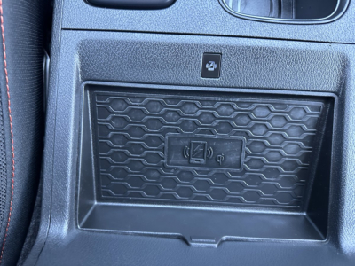 Center console area of a 2026 Nissan Frontier showing a wireless charging pad and a storage compartment with a textured insert.