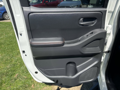 Frontier door panel interior with black plastic trim, armrest stitched in orange, window switch area, and lower storage pocket.