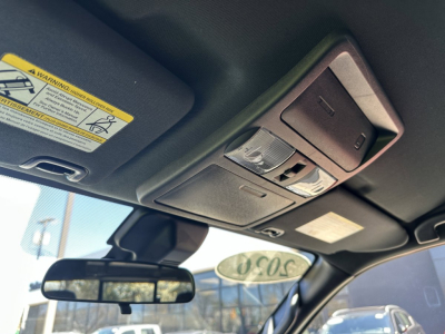 Interior roof console with sunroof/overhead lights and sunglasses holder in a Nissan Frontier cabin, with rearview mirror and windshield reflection.