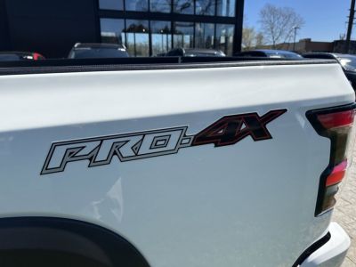 Rear side of a white Nissan Frontier Pro-4X pickup truck showing the Pro-4X badge on the tailgate.