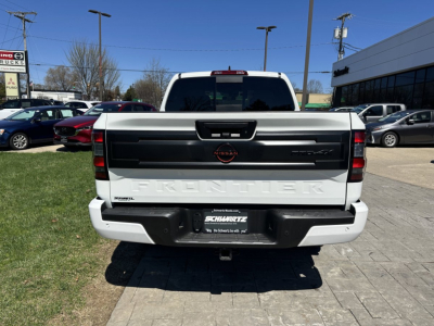 2026 Nissan Frontier rear view showing tailgate with 'Frontier' embossed and Nissan emblem, license area, and bumper. Vehicle in dealership lot.