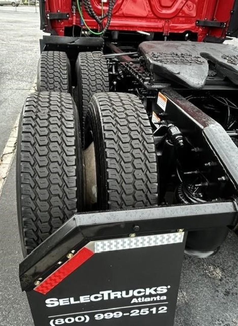 Dual rear truck tires and fifth-wheel area of a Freightliner Cascadia tractor showing dual rear axles and mudguard with SelectTrucks Atlanta branding.
