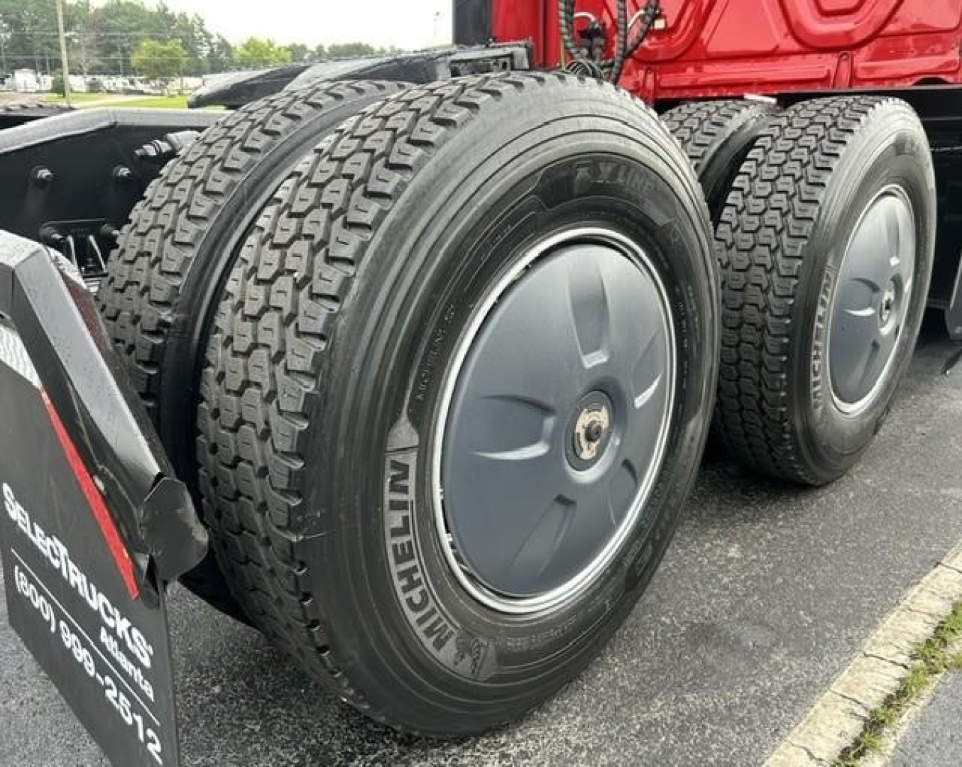 Dual rear truck wheels with Michelin tires on a Freightliner Cascadia sleeper tractor, visible tread pattern and hubcaps.