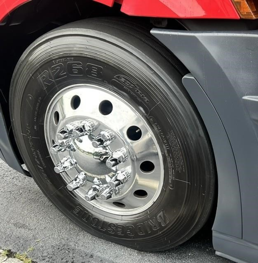Truck front wheel: large steel rim with chrome lug nuts, tire showing branding and numbers.