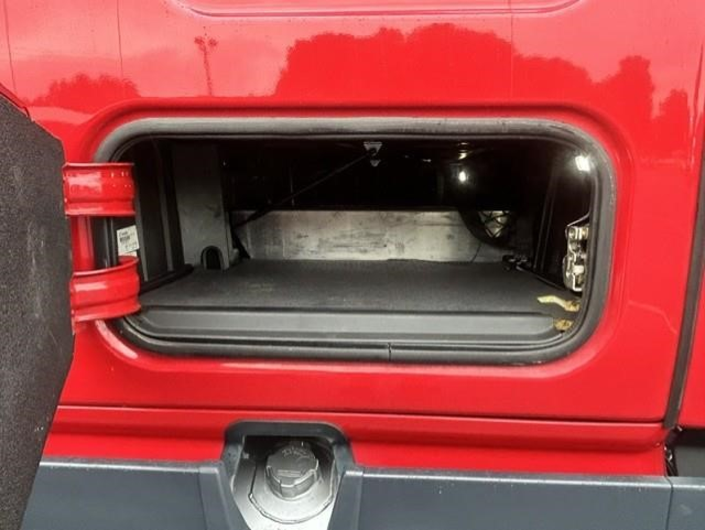 Freightliner Cascadia truck with open storage compartment under sleeper, showing interior including side walls and latch.