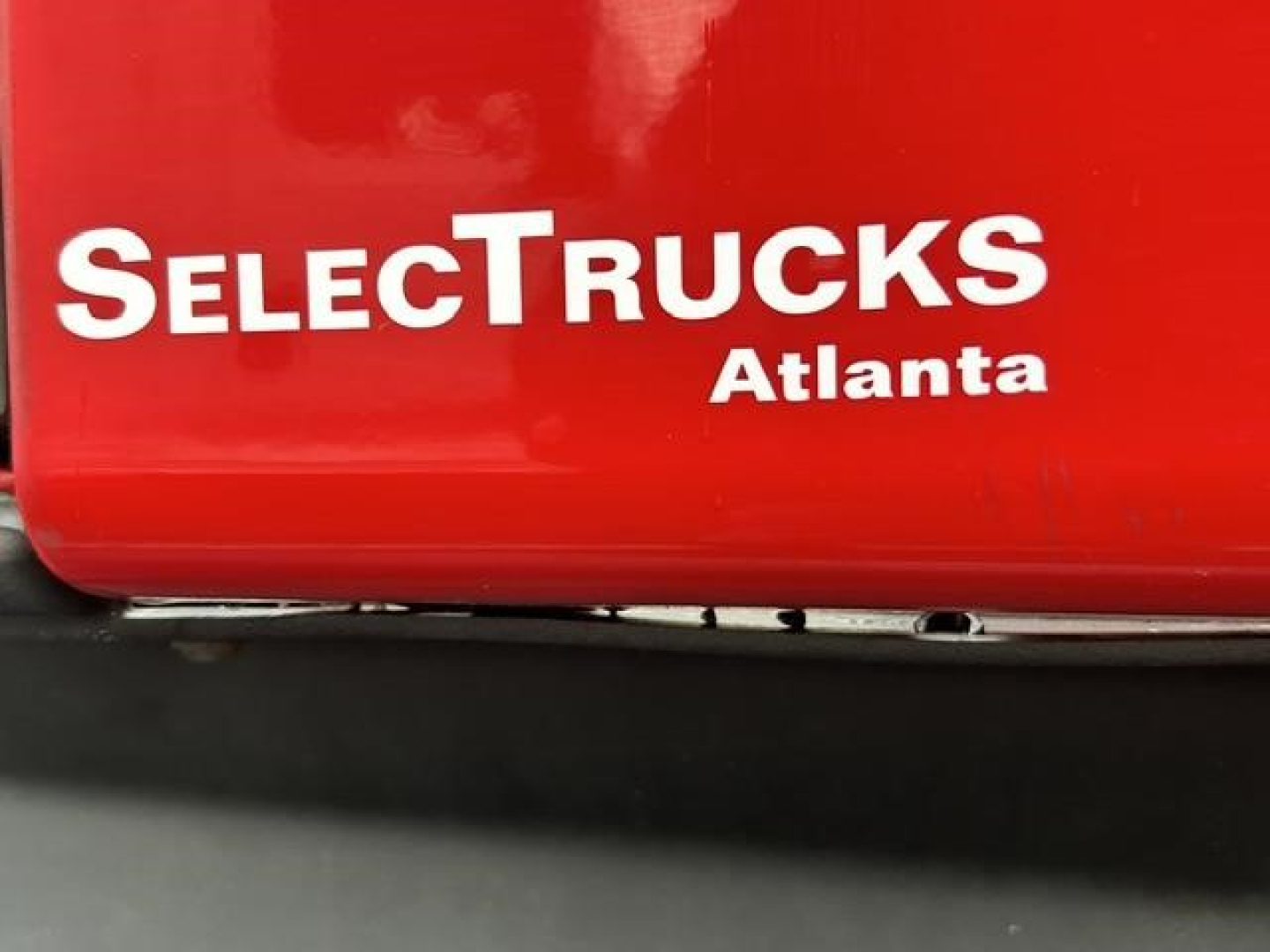 SelectTrucks Atlanta logo on red surface with partial text SelectTrucks and warehouse sticker, visible VIN, stock number, and vehicle category for a used 2023 Freightliner Cascadia.