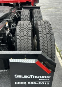 Truck rear showing dual rear axles with heavy tread tires and a SelecTrucks Atlanta plate.