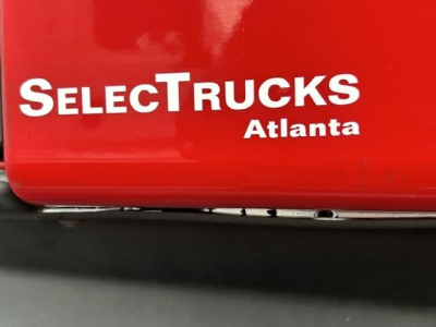 SelectTrucks Atlanta logo on red surface with partial text SelectTrucks and warehouse sticker, visible VIN, stock number, and vehicle category for a used 2023 Freightliner Cascadia.