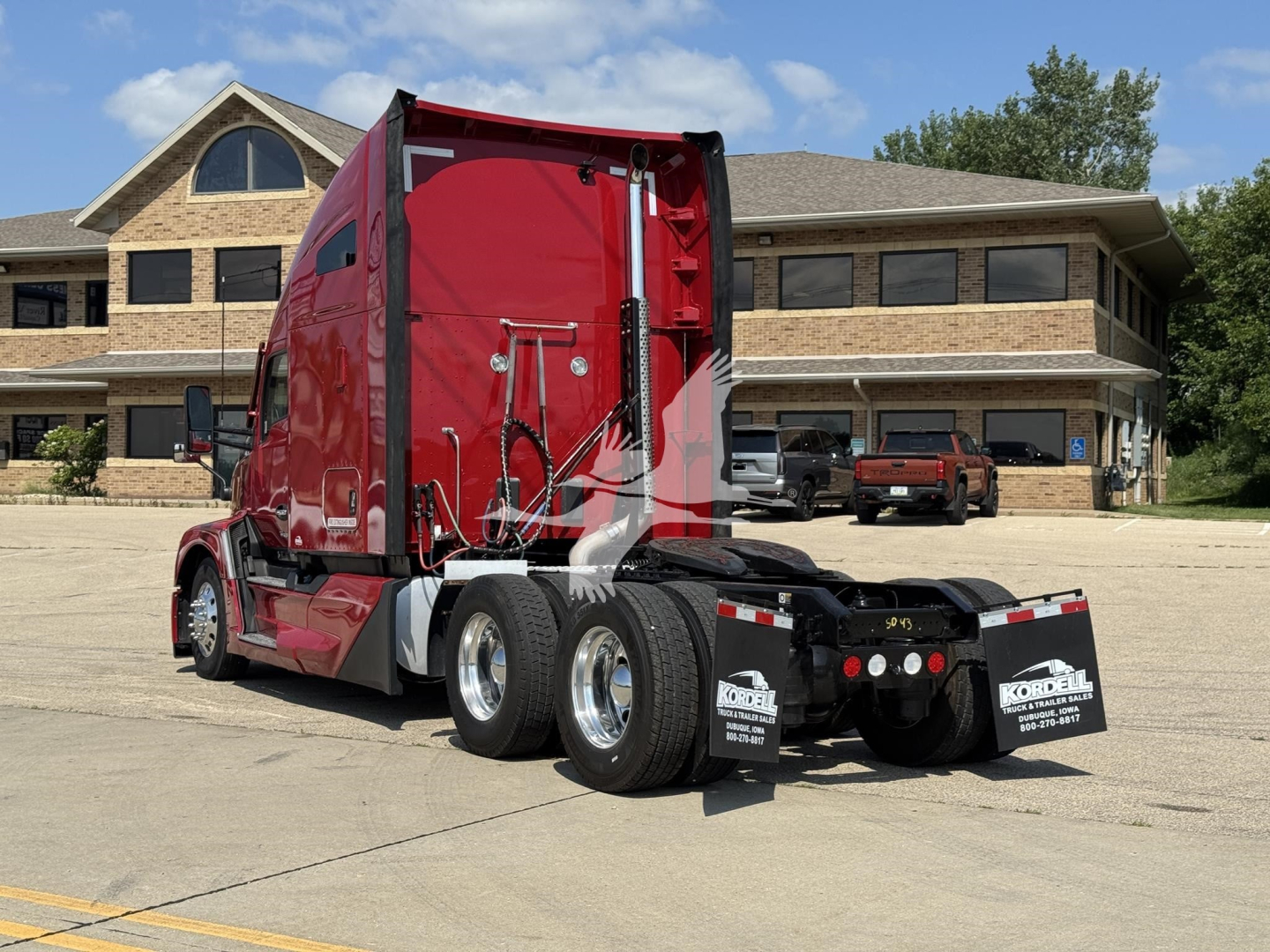 Kenworth truck tractor in a parking lot showing red sleeper cab and rear wheels