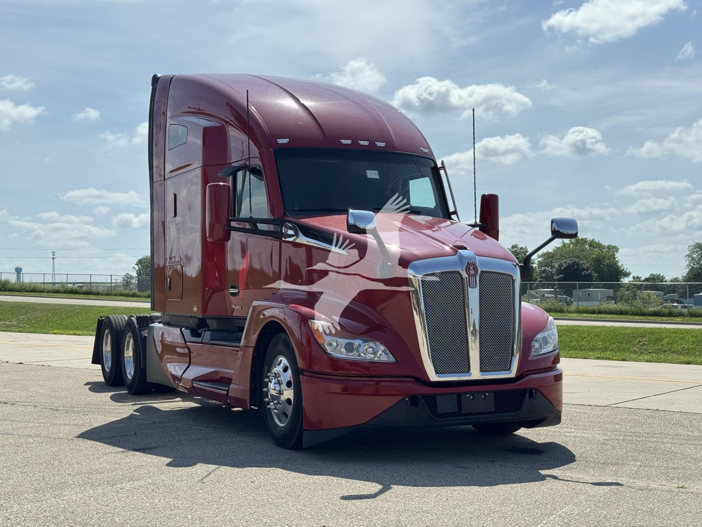 Kenworth T680 conventional sleeper truck in burgundy, front three-quarter view, showing chrome grille and headlights.