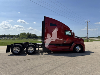 Kenworth T680 tractor in red showing side view with sleeper cab and 6-wheel rear chassis, no visible branding text captured.