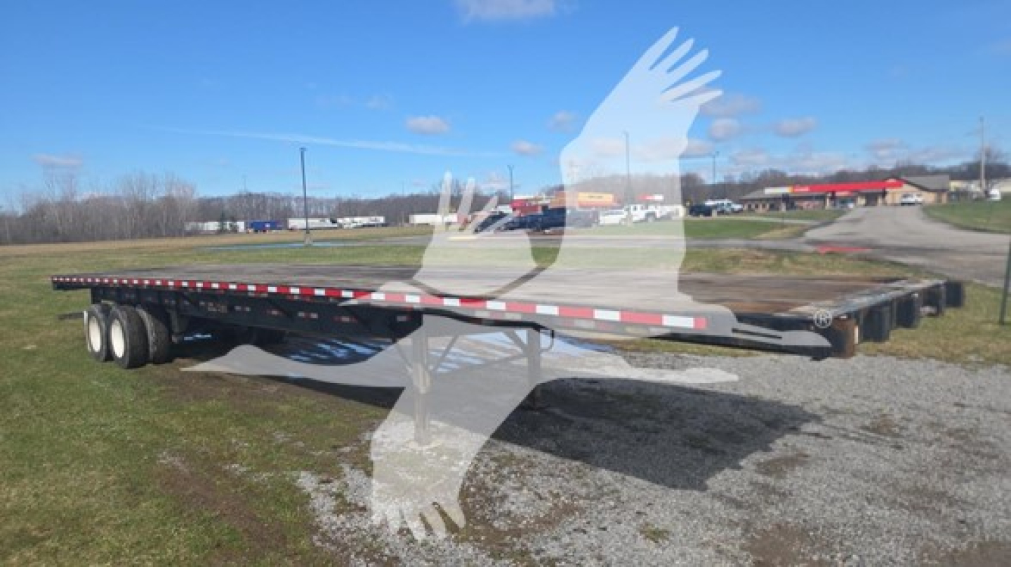 Great Dane steel flatbed trailer showing dual rear axles and long flat deck with red-white reflective tape along edge.