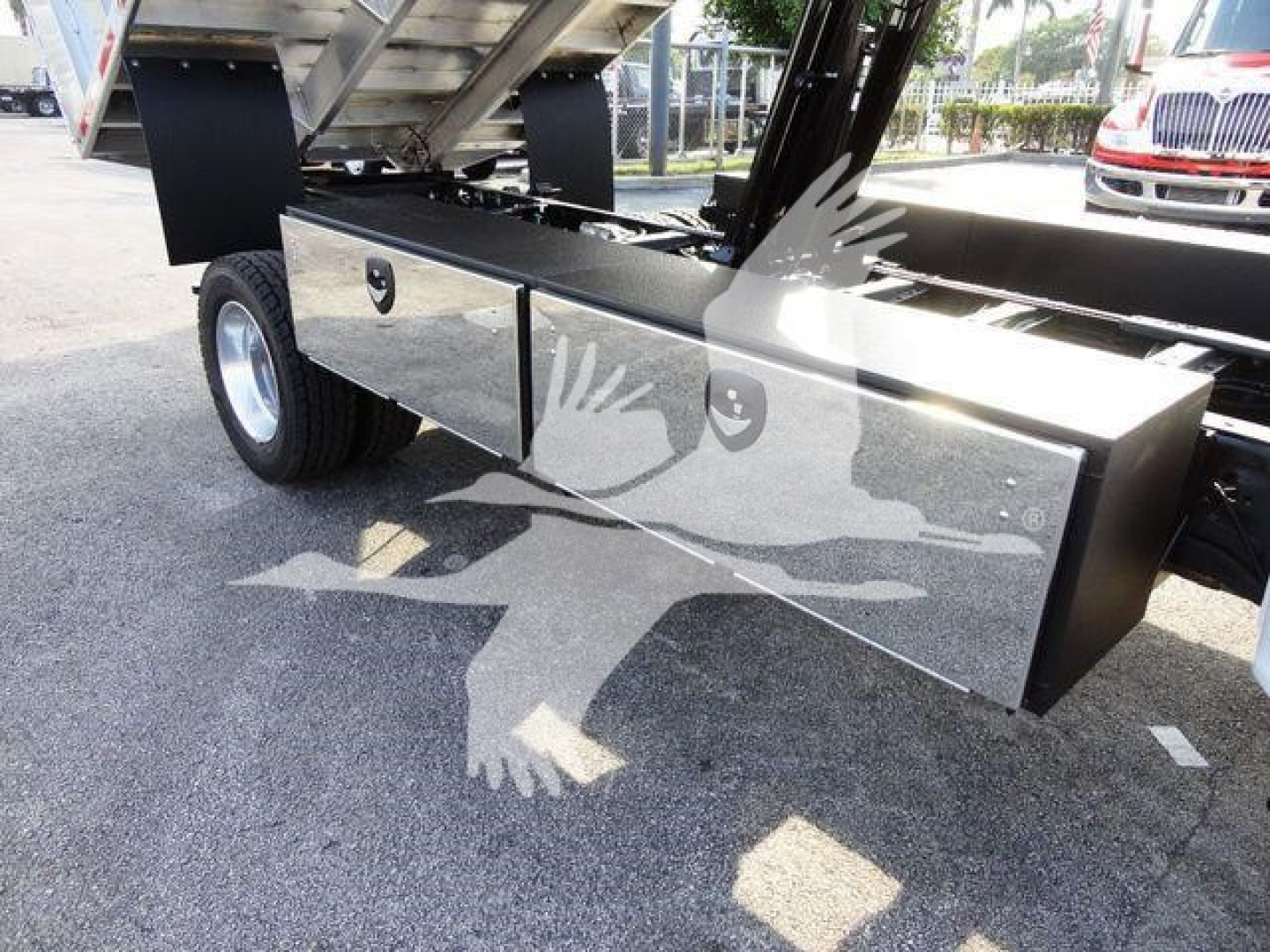 Chipper truck bed side toolbox with polished aluminum drawers on Ford F-600 chassis, underbody hydraulic components visible.
