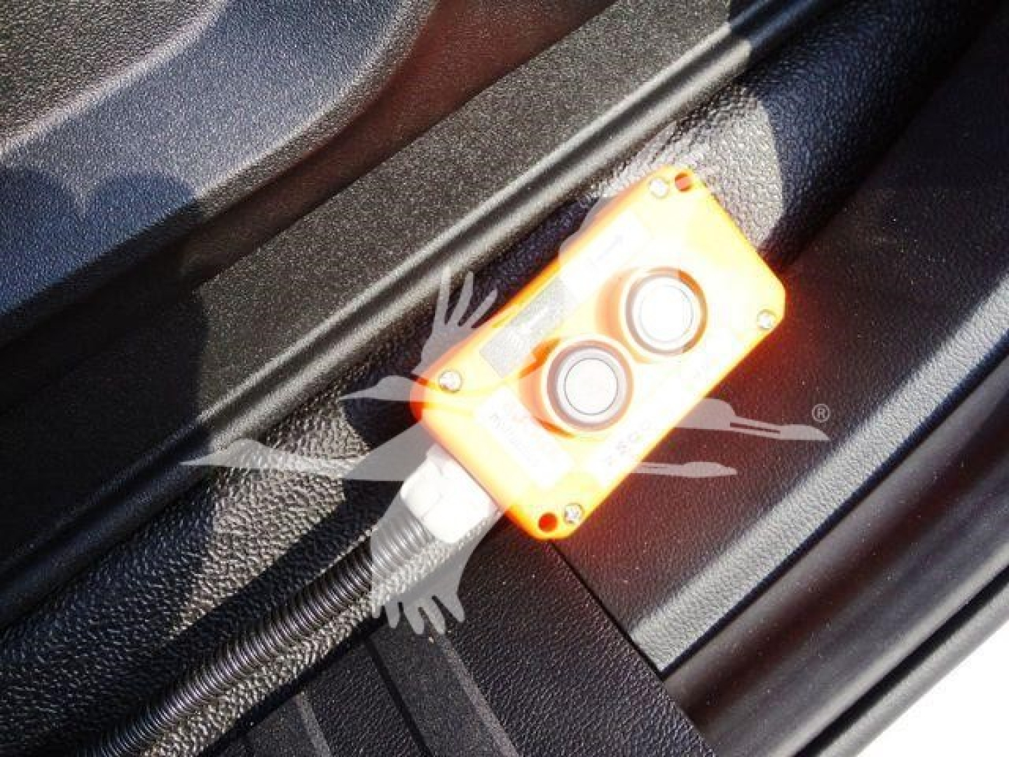Orange wireless remote control unit with two buttons in truck interior showing control box and wiring.