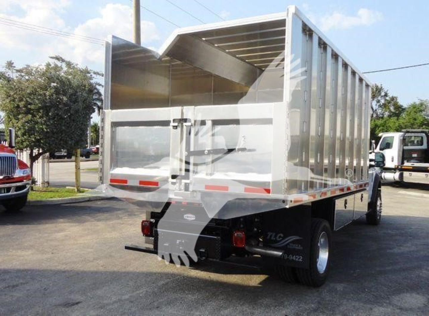 Rear/side view of a 2022 Ford F600 dump truck chassis with a silver aluminum dumping bed, showing dual rear tires and chipper/truck body.
