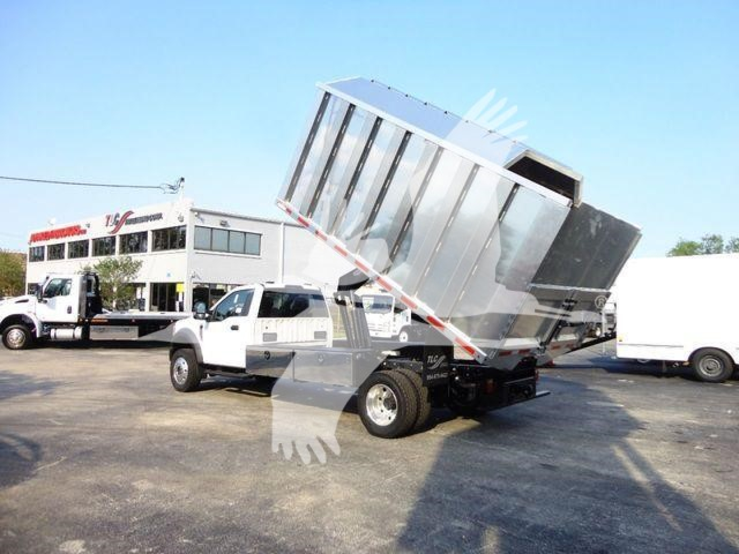 Ford F-600 cab and bed dump truck with raised dump bed in a dealership lot.