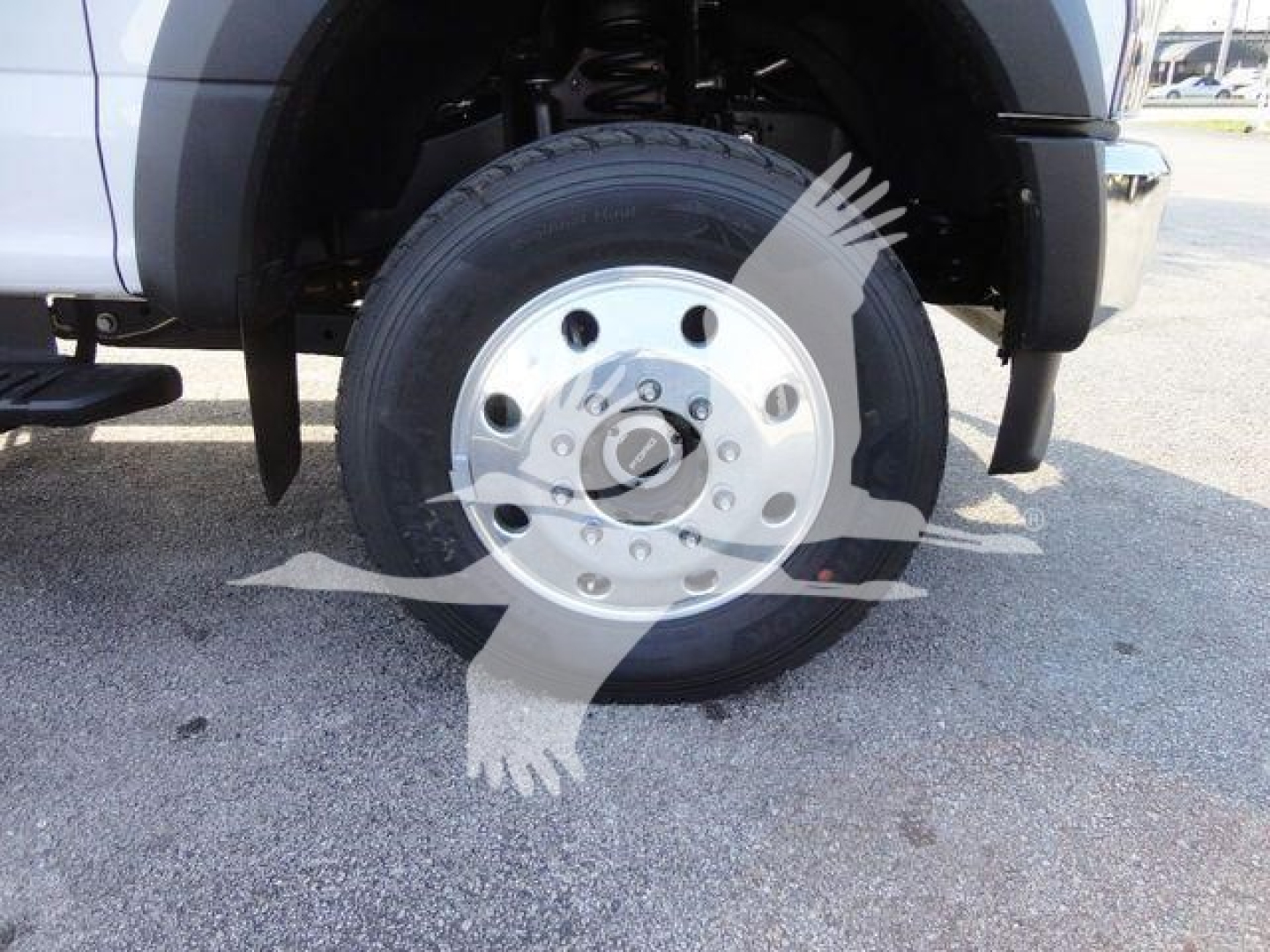 Ford F-600 front wheel and tire assembly showing 6-lug silver wheel with hub and part of front fender and suspension.