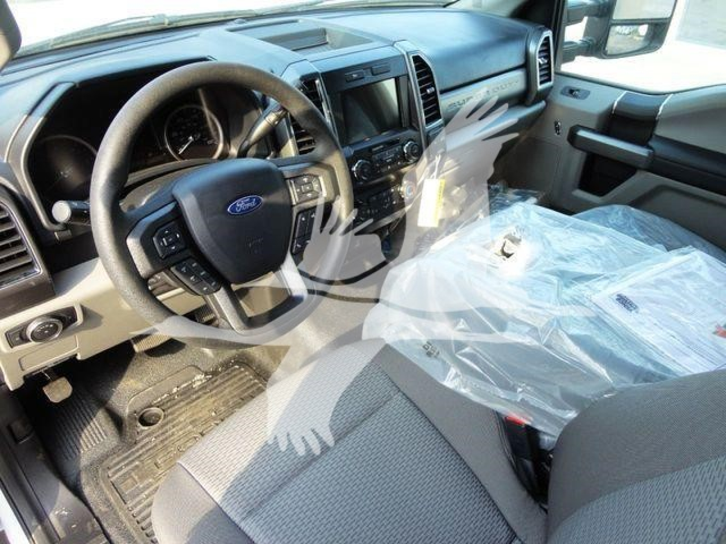 Ford F-600 truck interior showing steering wheel, dashboard, and front seats with plastic-covered seat.
