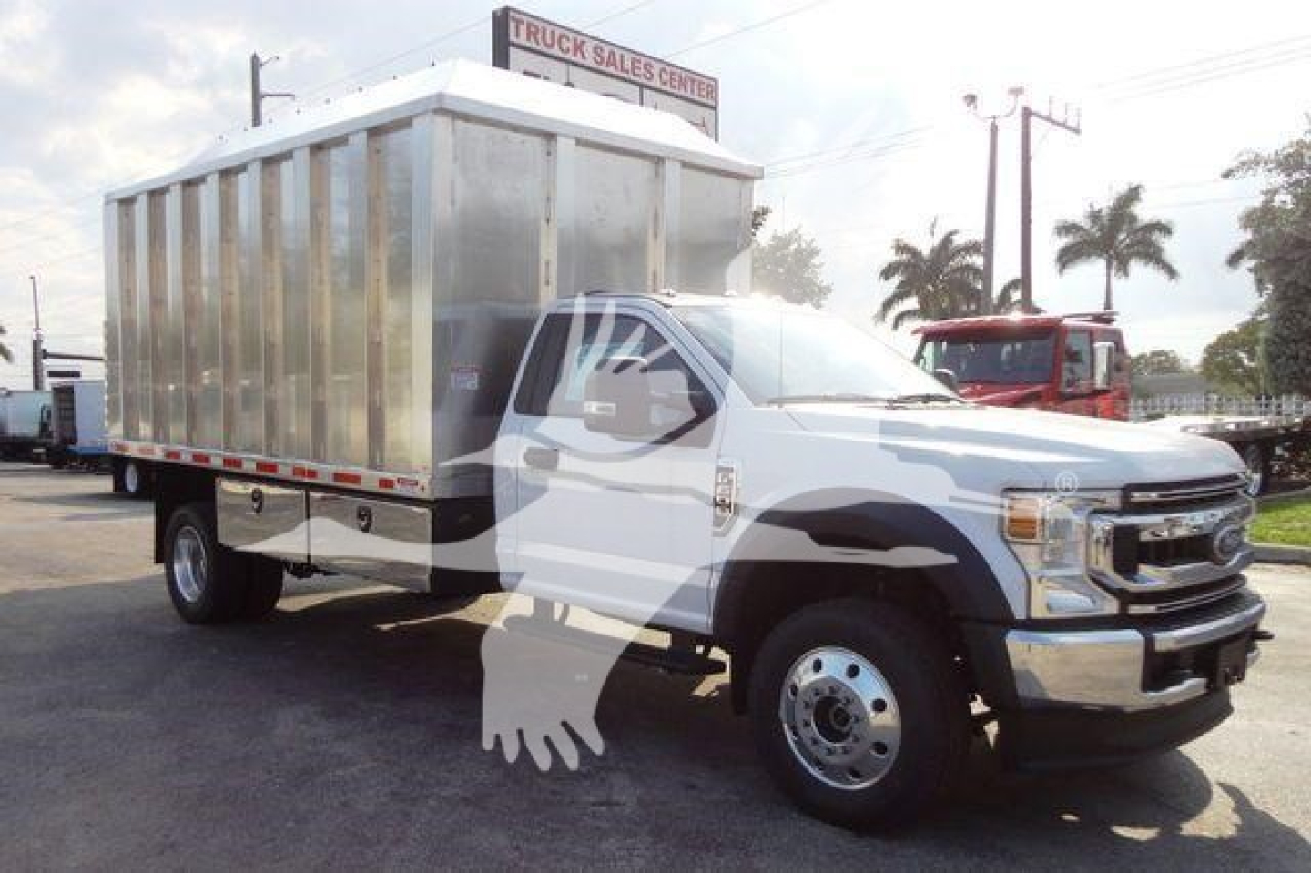Truck showing a 2022 Ford F600 chassis with a large aluminum dump body in a dealership lot.