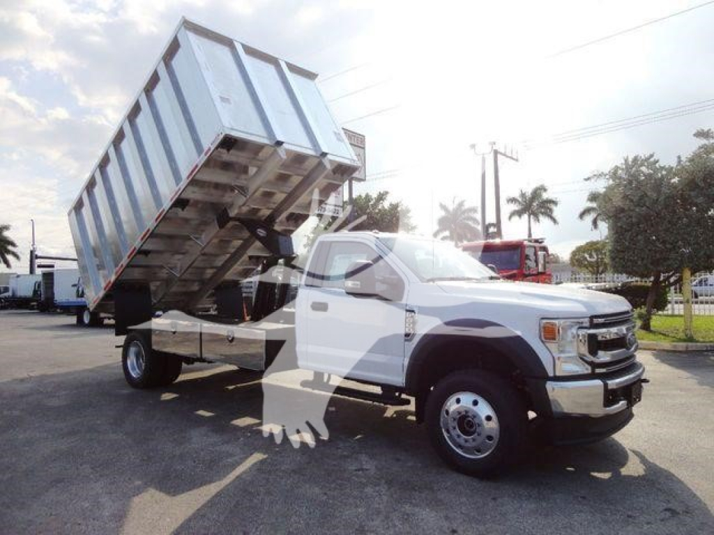 Ford F-600 dump truck with tilted metal bed on a pickup-style chassis, white cab, large dual rear wheels, heavy-duty utility vehicle in an outdoor lot.