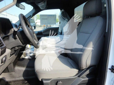 Ford F-600 cab interior showing gray fabric front seat and steering wheel in driver’s area.