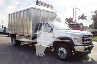 Truck showing a 2022 Ford F600 chassis with a large aluminum dump body in a dealership lot.