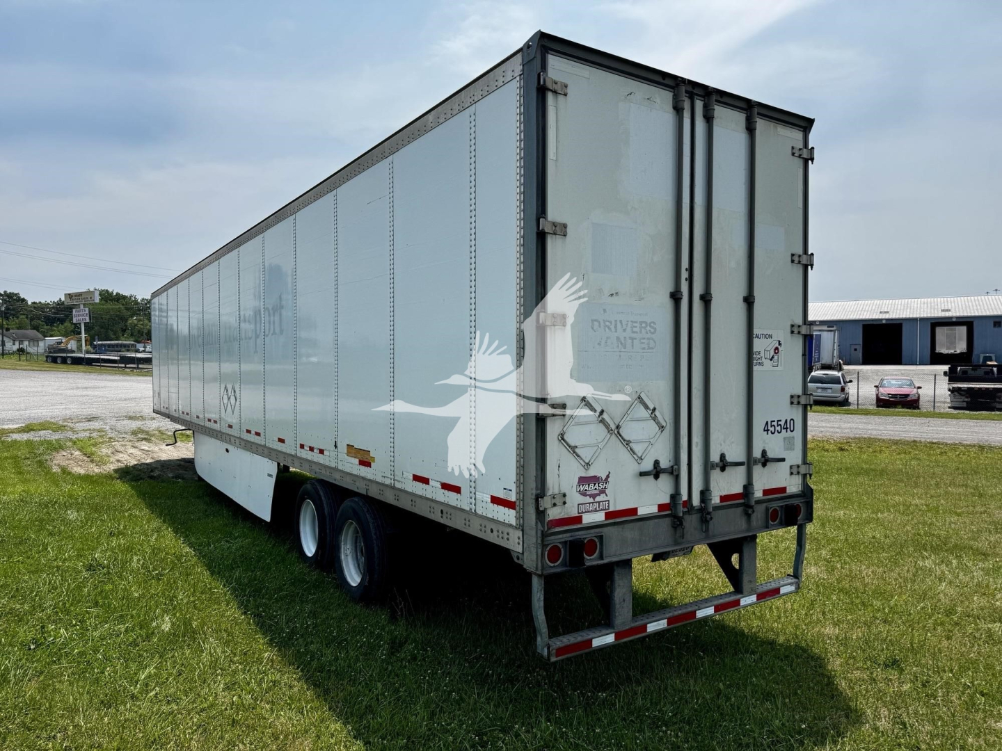 Wabash dry van trailer showing side panels, rear doors, and triple-axle setup. Visible text includes 'DRY VAN' branding and serial markings on rear.