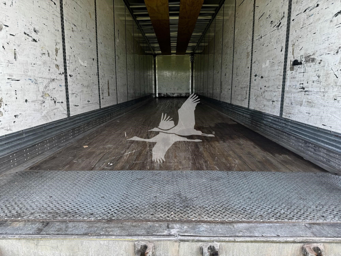 Trailer interior showing empty Wabash dry van cargo area with wood floor, side walls, and bulkhead, from open rear doors.