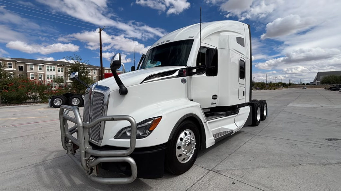 Kenworth T680 tractor-trailer cab in white with front bull guard and side sleeper, daytime with blue sky