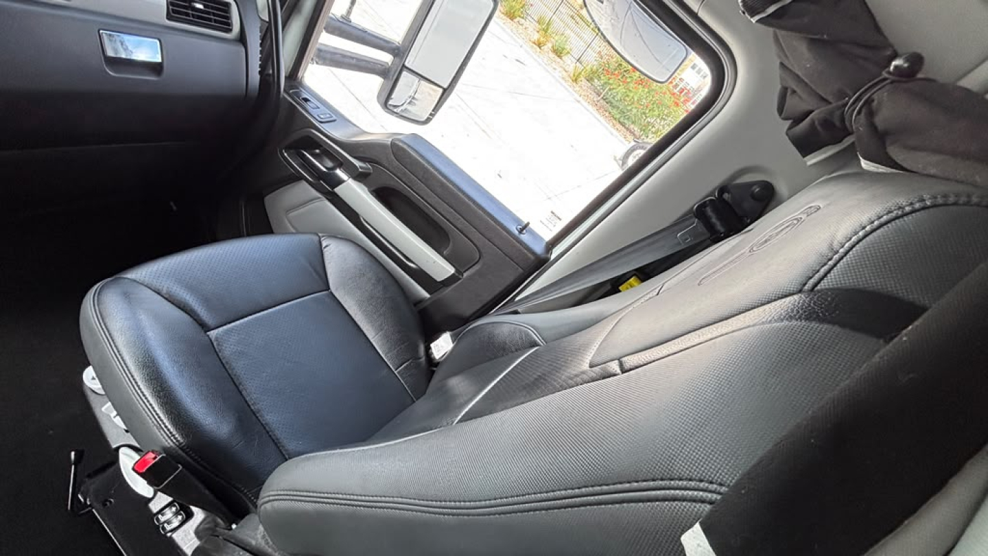 Kenworth T680 cabin interior showing driver's seat and dashboard area, with steering wheel and window controls visible.