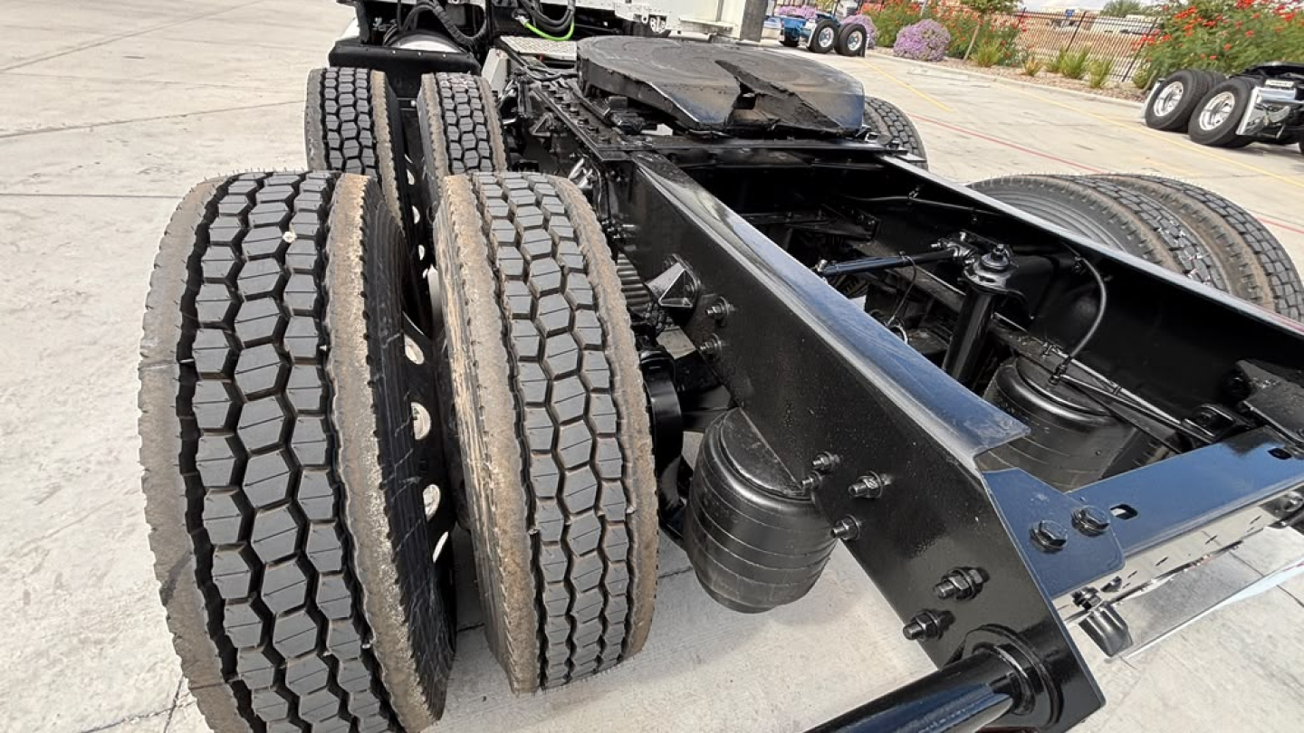 Kenworth T680 chassis and dual rear axles with dual tires in view; black framing and suspension components visible.