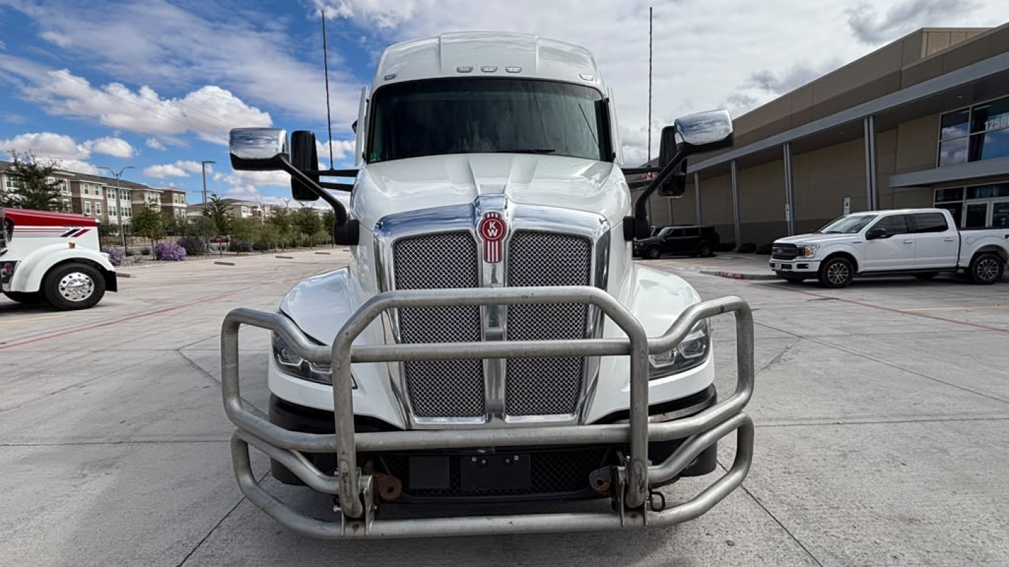 Kenworth T680 front view showing large grille and bull bar guard with chrome bumper, two side mirrors, heavy-duty grille guard, and clear sky background.
