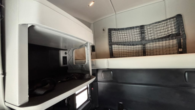 Kenworth T680 cab interior showing sleeper area with storage shelf and window net.