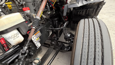 Kenworth T680 front cab area showing engine bay components, coolant reservoir labeled 'RACOR' and various hoses and wiring.