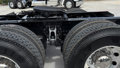 Kenworth T680 tractor rear view showing tandem axle setup, middle pin, air lines, and suspension components between dual rear tires.