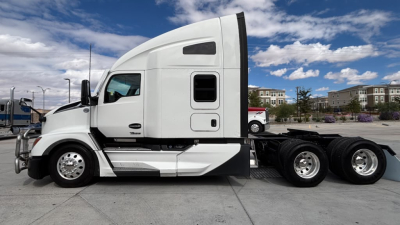 Kenworth T680 conventional sleeper tractor side view showing cab with window, door, and side panel; white paint; three rear axles with dual tires.