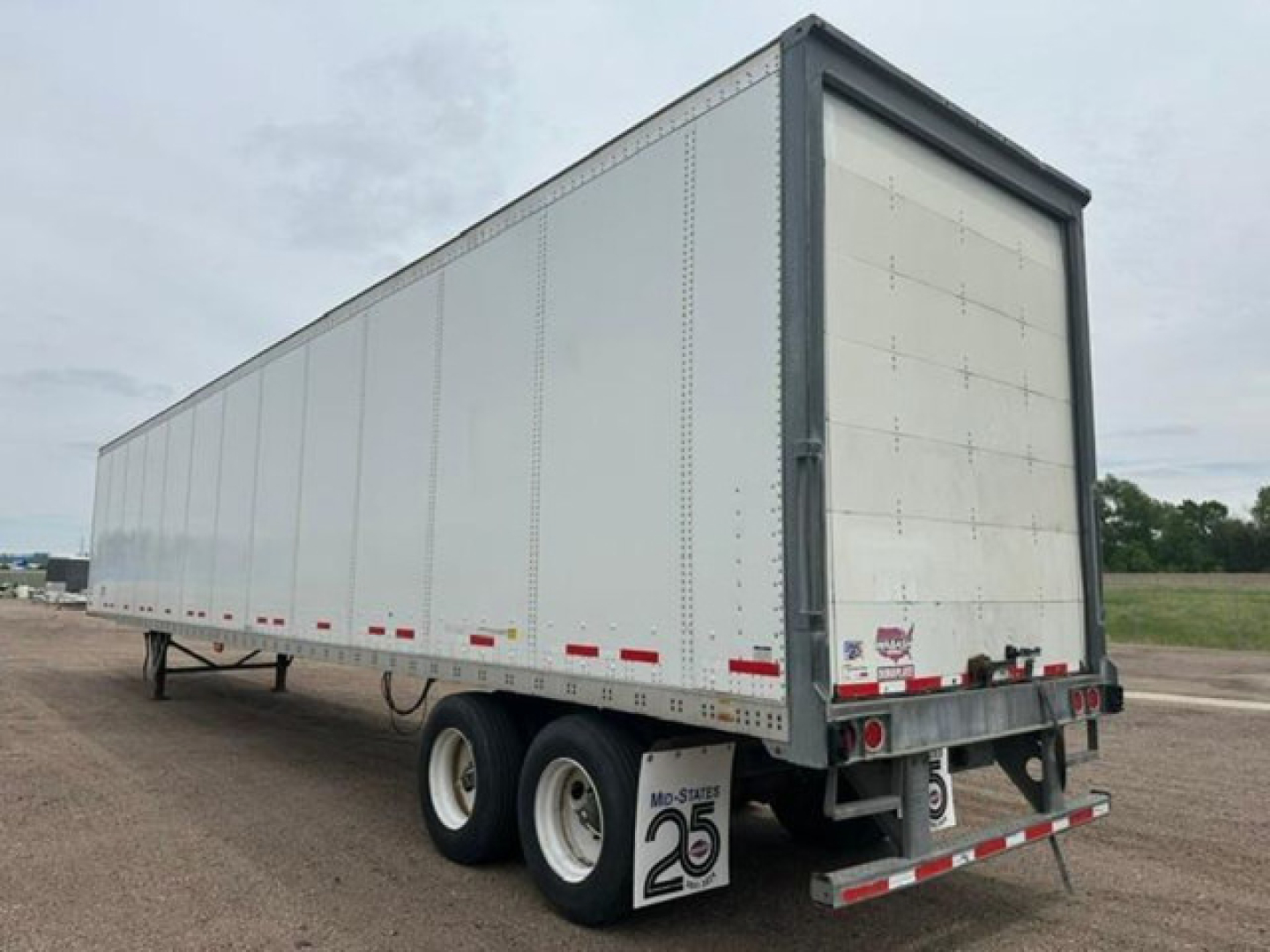 Trailer side view showing a 2016 Wabash box trailer with white exterior, double rear doors, tandem axles, and rear underride guard.