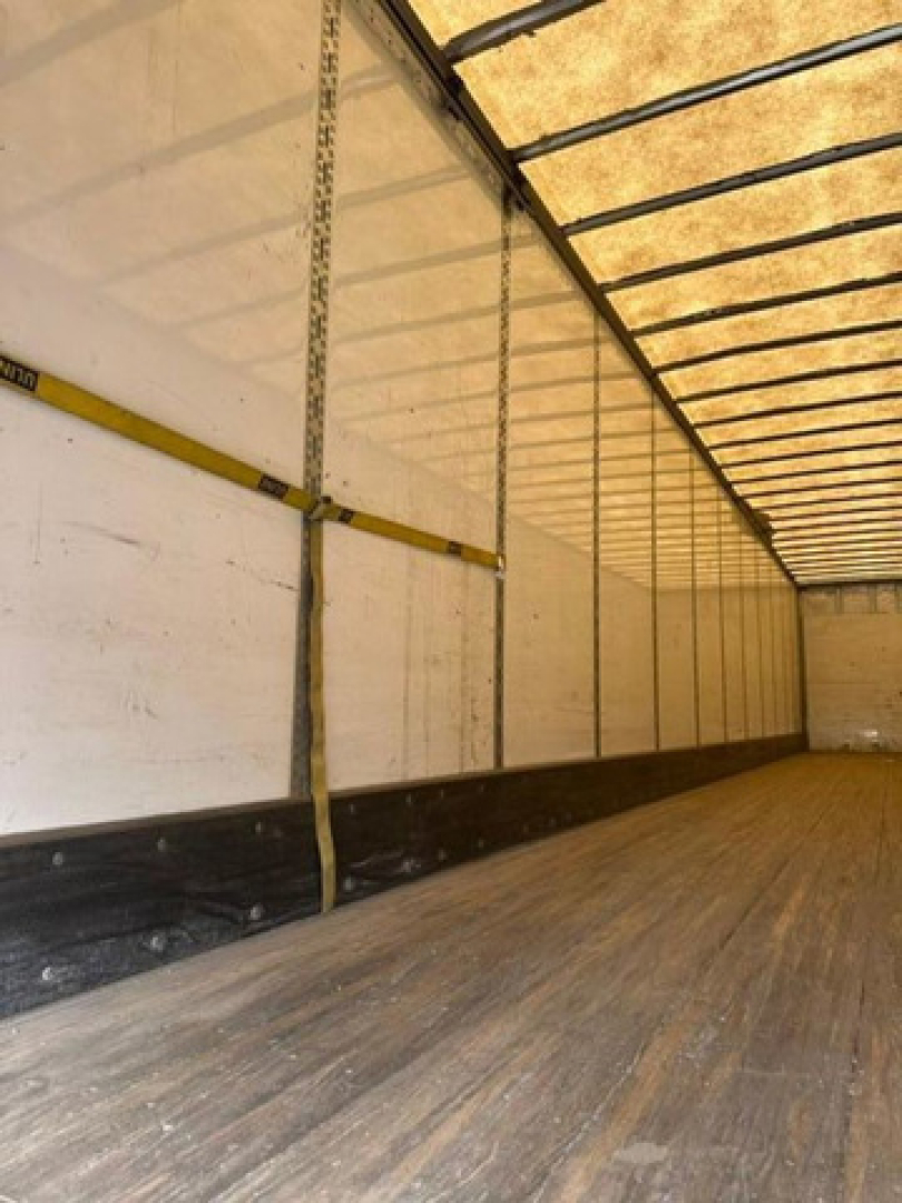 Trailer interior showing wood floor and sidewall with vertical straps and cargo rails in a Wabash van trailer.
