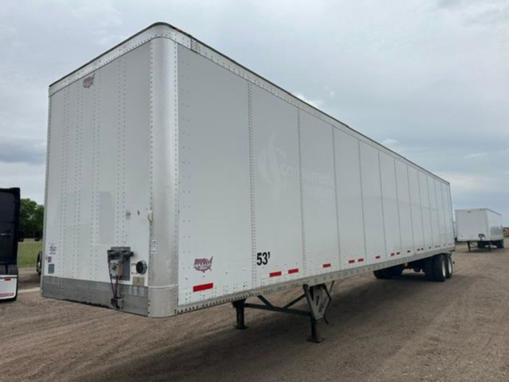 Trailer side view showing 53' box and landing gear of a white Wabash van trailer in a gravel lot.