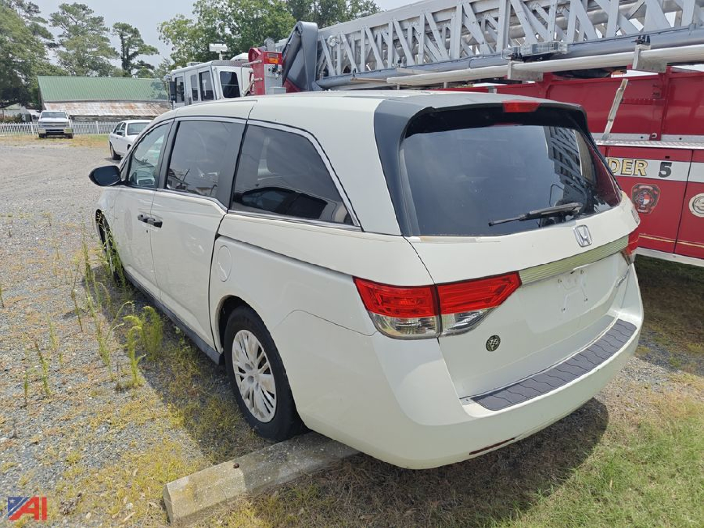 Honda Odyssey minivan rear three-quarter view showing white exterior, tinted windows, and rear hatch in a parking lot.