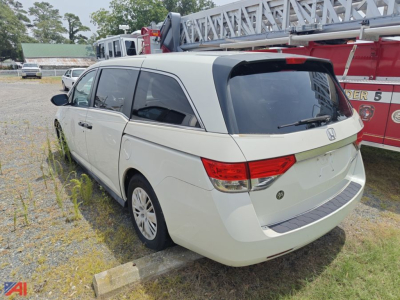 Honda Odyssey minivan rear three-quarter view showing white exterior, tinted windows, and rear hatch in a parking lot.